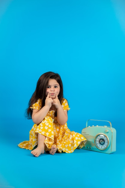 Happy cute baby girl vêtements de bébé jaune à la mode posant studio sur fond bleu
