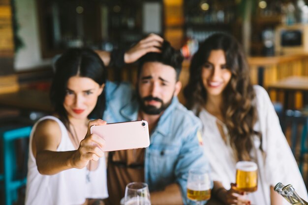 Happy friends in bar posant pour selfie