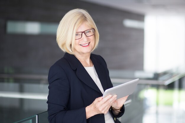 Happy Senior Business Lady Using Tablet dans Lobby