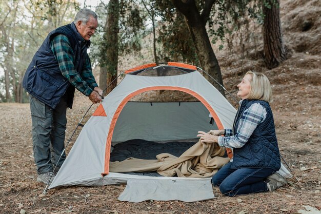 Happy senior couple installer une tente dans la forêt