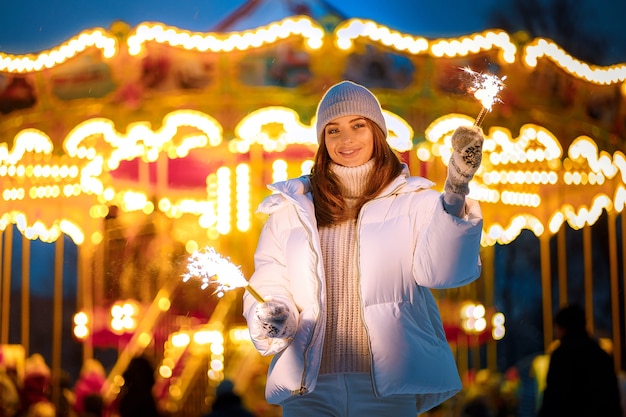 Happy smiling caucasian young woman burns cierges magiques par l'éclairage de vacances le jour de l'an