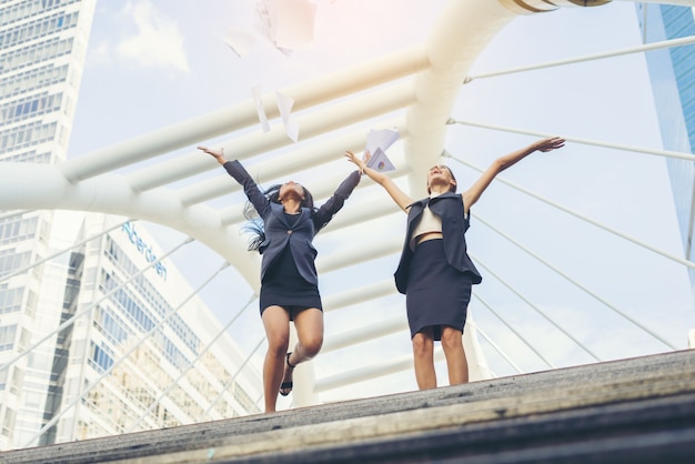 Happy Success Businesswomen surplombant les jumelles dans les mains du centre-ville levées.