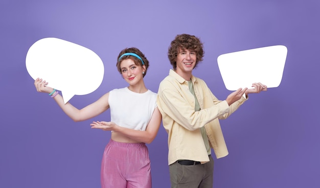 Happy teen couple holding bulles vides sur fond violet