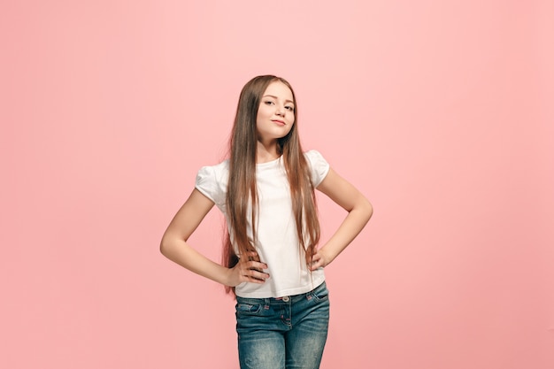 Happy teen girl debout, souriant isolé sur fond de studio rose à la mode.