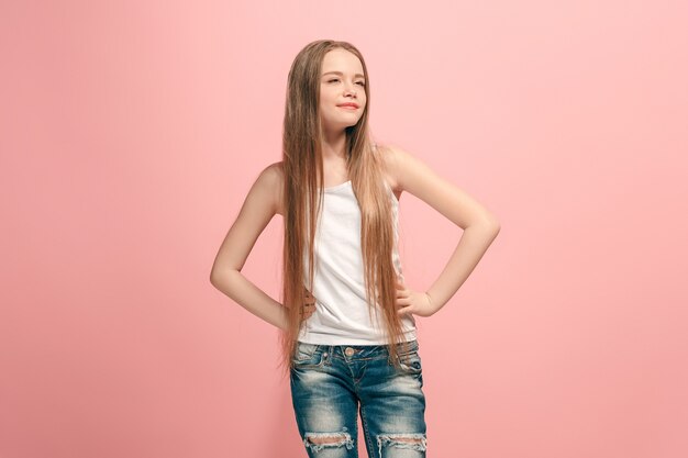 Happy teen girl debout, souriant isolé sur fond de studio rose à la mode.