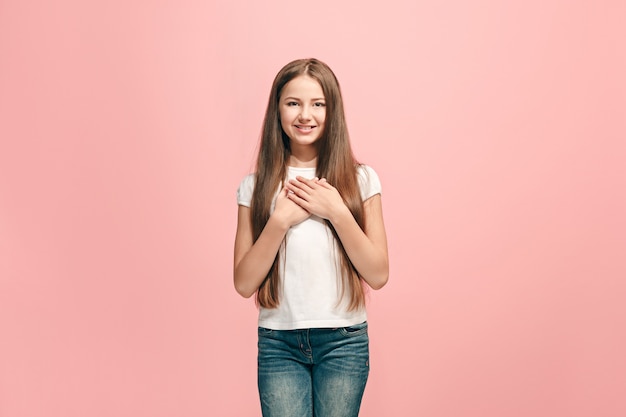 Happy teen girl debout, souriant isolé sur un studio rose à la mode