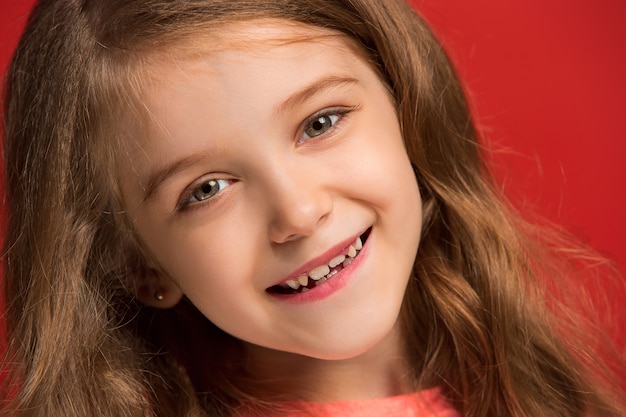 Happy teen girl debout, souriant isolé sur un studio rouge à la mode