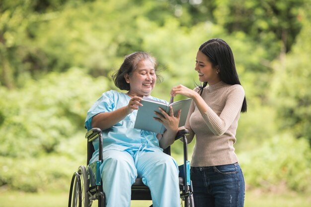 Happy Woman en fauteuil roulant, lisant un livre avec sa fille au parc