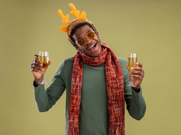 Homme Afro Americain Avec Jante Drole Avec Des Cornes De Cerf Et Une Echarpe Autour Du Cou Tenant Un Verre De Champagne En Le Regardant Intrigue Debout Sur Fond Vert Photo Gratuite Homme Afro Americain Avec Jante Drole Avec Des Cornes De Cerf Et Une Echarpe Autour Du Cou Tenant Un Verre De Champagne En Le Regardant Intrigue Debout Sur Fond Vert Photo Gratuite