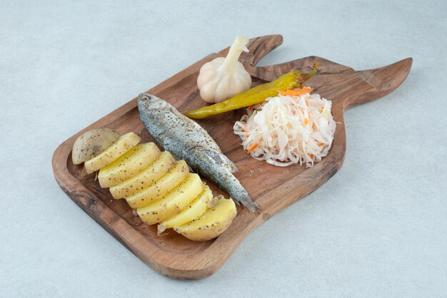 Hareng, pommes de terre bouillies et cornichons mixtes sur planche de bois.