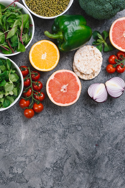 Photo gratuite haricot mungo; épinard; agrumes; gâteau de riz soufflé et légumes frais sur fond de béton