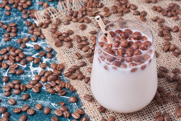 Haricots au chocolat avec une tasse de boisson sur bleu.