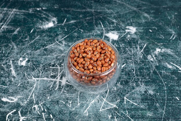 Haricots bruns dans une tasse en verre sur fond bleu. Photo de haute qualité