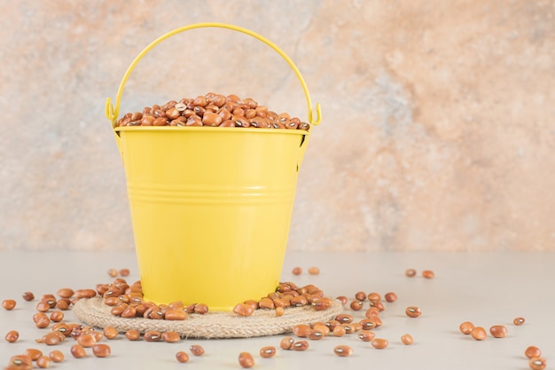 Haricots bruns isolés dans une tasse en céramique sur béton.