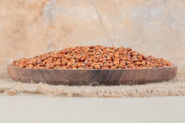 Haricots bruns isolés sur une planche de bois sur du béton.