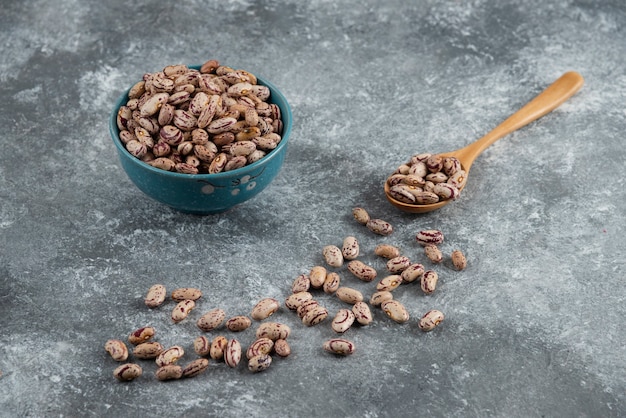 Photo gratuite haricots crus et cuillère en bois sur marbre.