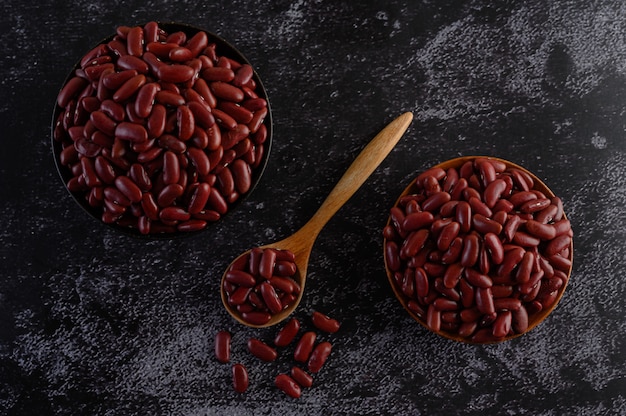 Photo gratuite haricots rouges dans un bol en bois et une cuillère en bois sur le sol en ciment noir.