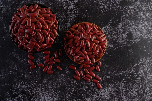 Haricots rouges dans un bol en bois sur le sol en ciment noir.