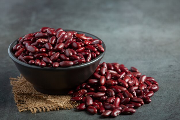 Haricots rouges dans un petit bol noir place sur un sol sombre