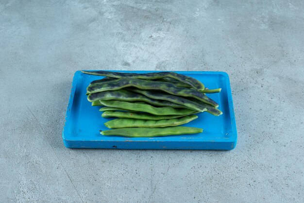 Haricots verts biologiques sur plaque bleue.