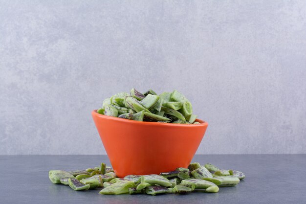 Haricots verts hachés à l'intérieur d'une tasse sur une surface bleue