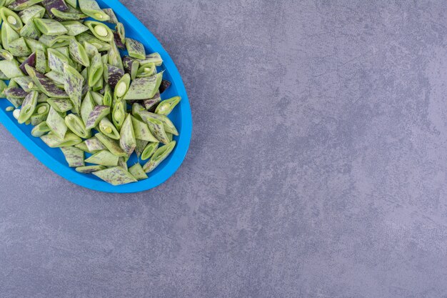 Haricots verts isolés dans un plateau en bois sur une surface bleue