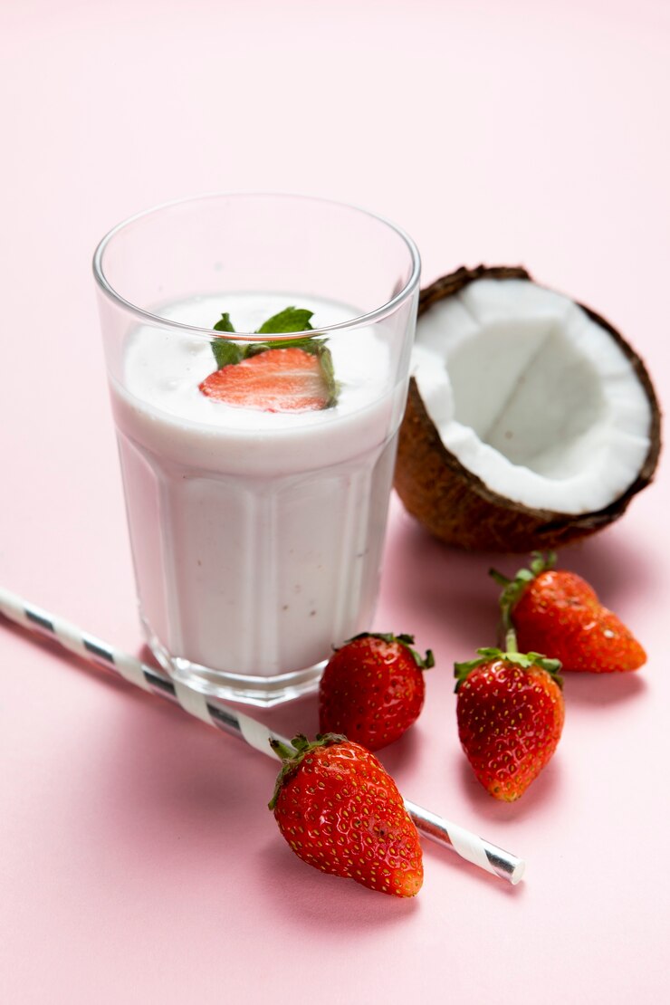 Photo gratuit haut angle de verre aux fraises et au lait sur fond uni