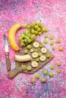 Photo gratuite haut de la page vue lointaine fruits frais en tranches de raisins et de bananes sur la couleur de jus moelleux de fruits de surface pourpre