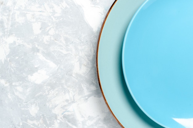 Photo gratuite haut de la page vue rapprochée des assiettes rondes vides de couleur bleu sur plaque murale blanche cuisine couverts en verre de couleur