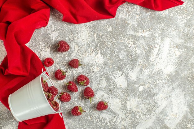 Haut de la page vue rapprochée d'un bol de framboises allongé sur une serviette rouge sur un backgorund en marbre