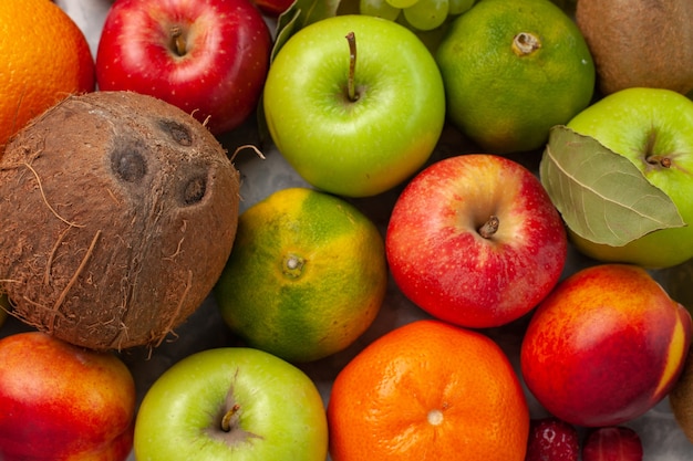 Photo gratuite haut de la page vue rapprochée de la composition des fruits différents fruits frais sur le bureau blanc fruits frais couleur d'été doux