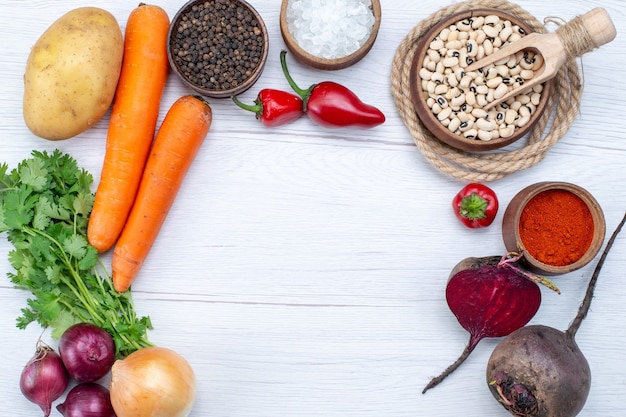 Haut de la page vue rapprochée de la composition végétale avec des légumes frais verts haricots crus carottes et pommes de terre sur un bureau léger