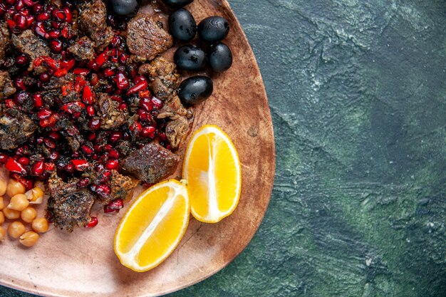 Haut de la page vue rapprochée de délicieuses tranches de viande frites avec des raisins de haricots et des tranches de citron à l'intérieur de la plaque sur fond sombre