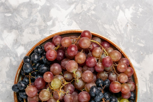 Haut de la page vue rapprochée de différents raisins juteux fruits aigres moelleux sur un bureau blanc léger fruits frais de jus de vin