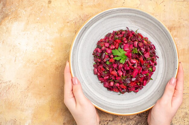 Haut de la page vue rapprochée du bol d'une salade rouge avec des verts dessus sur un backgorund en bois