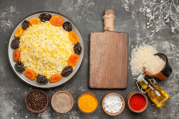 Haut de la page vue rapprochée du riz la planche à découper épices assiette de riz aux fruits secs huile bol de riz