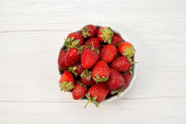 Haut de la page vue rapprochée de fraises rouges fraîches moelleuses et délicieuses baies à l'intérieur de la plaque blanche sur la lumière, fruit berry couleur rouge frais