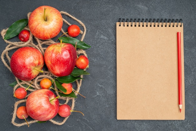 Haut de la page vue rapprochée fruits cerises corde pommes rouge-jaune avec des feuilles crayon de cahier