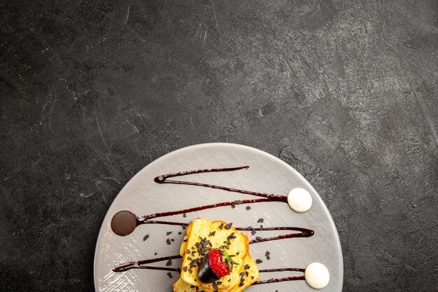 Haut de la page vue rapprochée gâteau dessert avec fraises enrobées de chocolat et sauce au chocolat sur la table noire