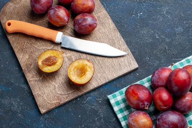 Haut de la page vue rapprochée de prunes fraîches entières moelleuses et juteuses sur un bureau sombre, fruits frais couleur vitamine été