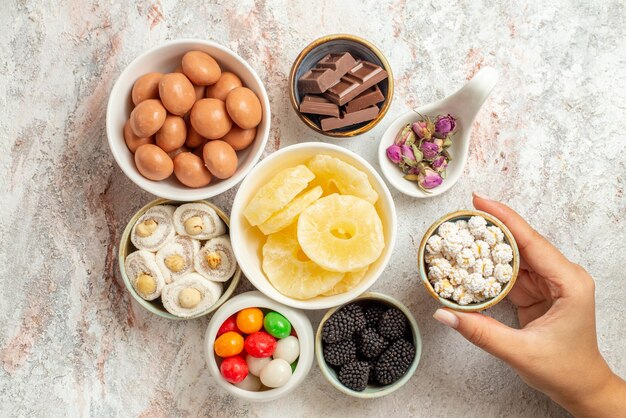 Haut vue en gros plan des bonbons dans des bols les bols de bonbons appétissants fruits secs et baies dans la main