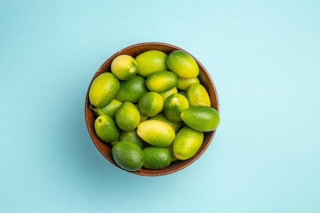 Haut vue rapprochée fruits fruits verts dans un bol sur la surface bleue