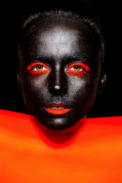 Haute couture look.glamour fashion belle femme américaine noire en masque noir avec un maquillage lumineux orange et des lèvres orange avec un matériau orange