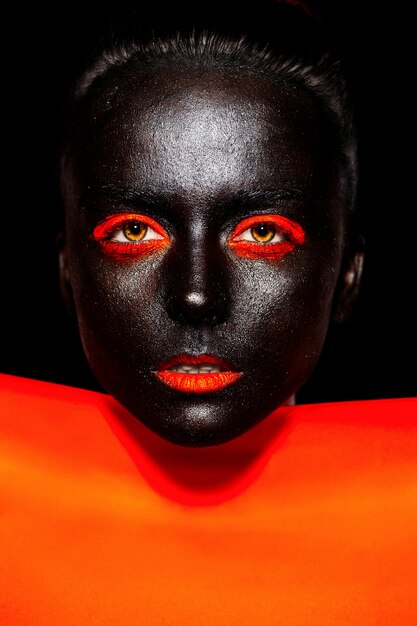 Haute couture look.glamour fashion belle femme américaine noire en masque noir avec un maquillage lumineux orange et des lèvres orange avec un matériau orange