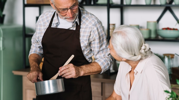 Photo gratuite haute femme regardant un homme préparant un repas dans la cuisine