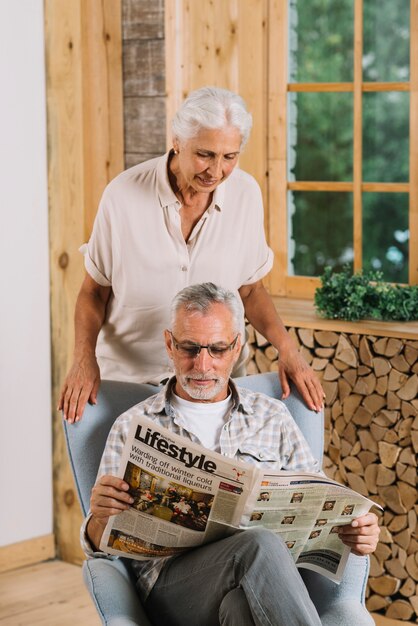 Haute femme regardant son mari lisant un journal à la maison