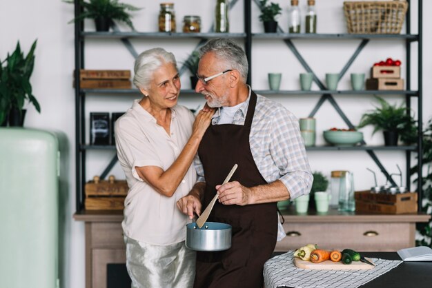 Haute femme regardant son mari préparer un repas dans la cuisine