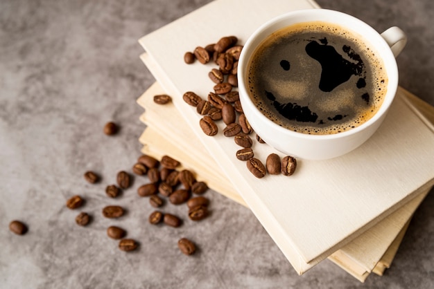 Photo gratuite haute vue tasse de café sur des livres