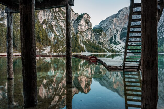 Hautes montagnes rocheuses reflétées dans le lac Braies avec des escaliers en bois près de la jetée en Italie