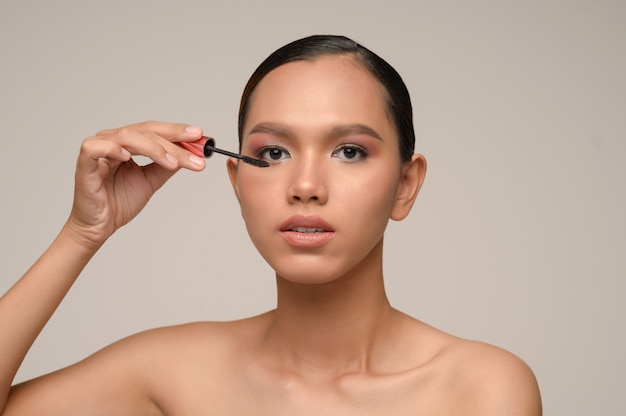 Head shot, portrait young Asian woman With Beautiful Face et brosse à mascara à la main